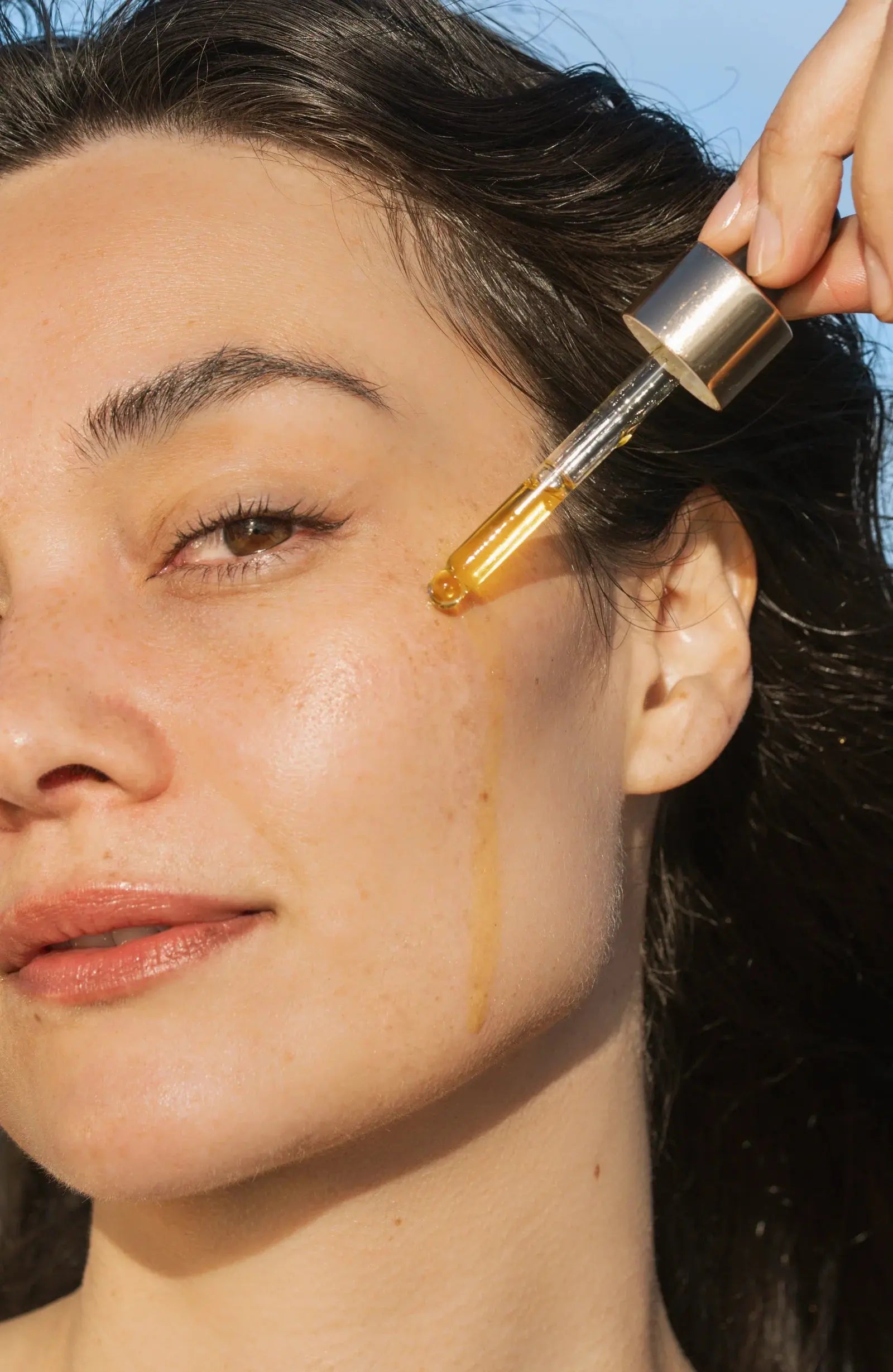 Women applying face oil with dropper