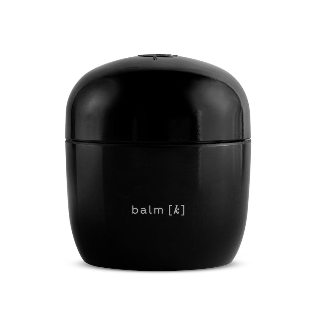 A black jar of balm, labeled 'balm [k]', against a white background.