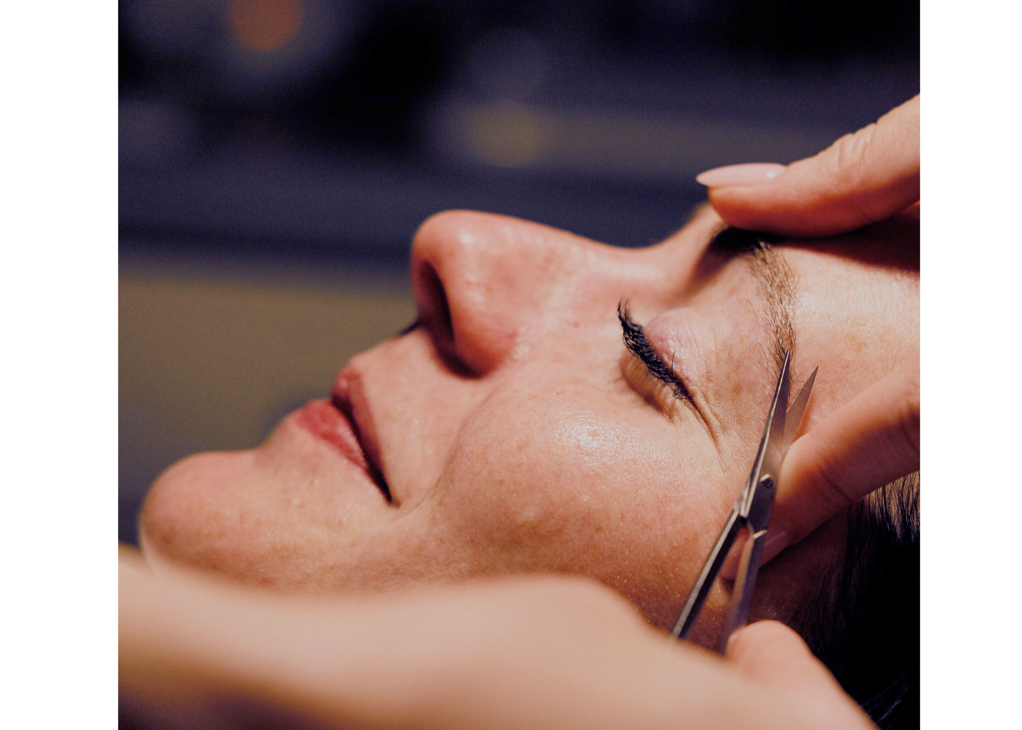 Close-up of a person getting a brow shaping with tiny scissors.