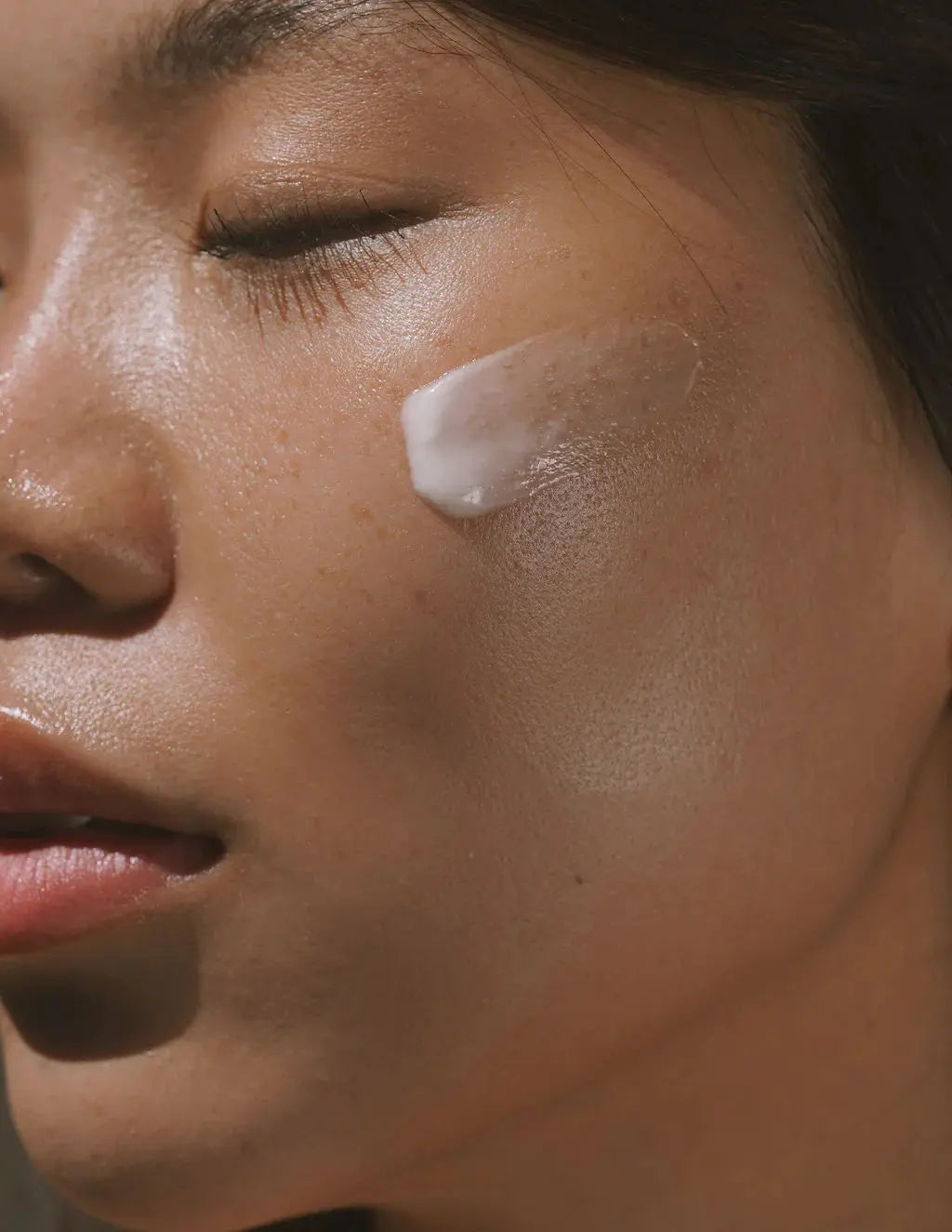 Woman with creamy serum on cheekbone