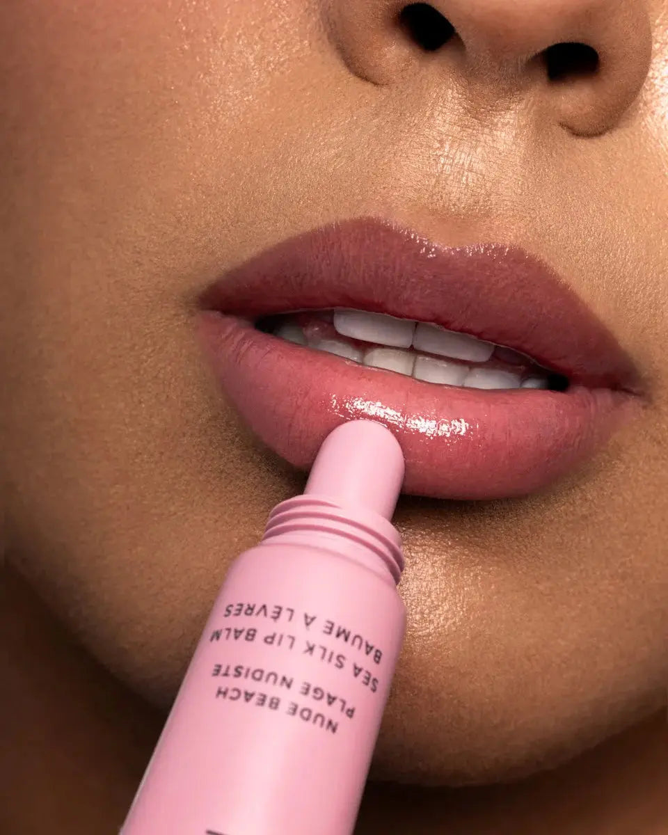 Close-up of a person applying a pink lip balm to their lips.
