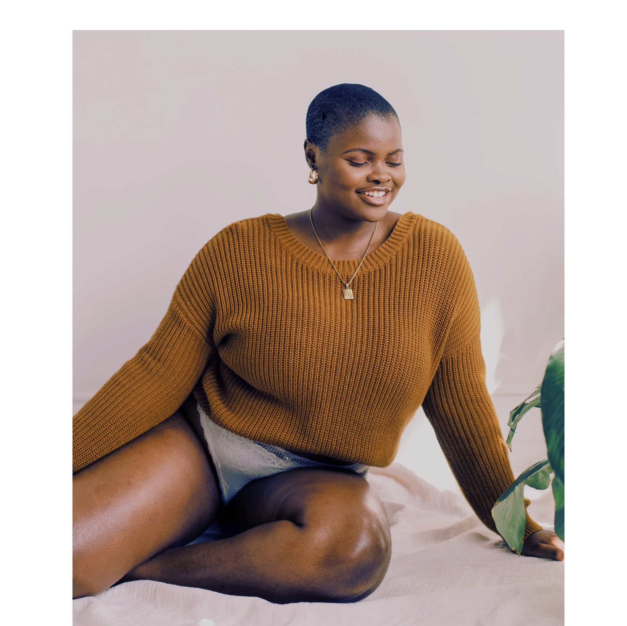 Woman wearing a yellow sweater, white briefs and gold jewelry on a bed