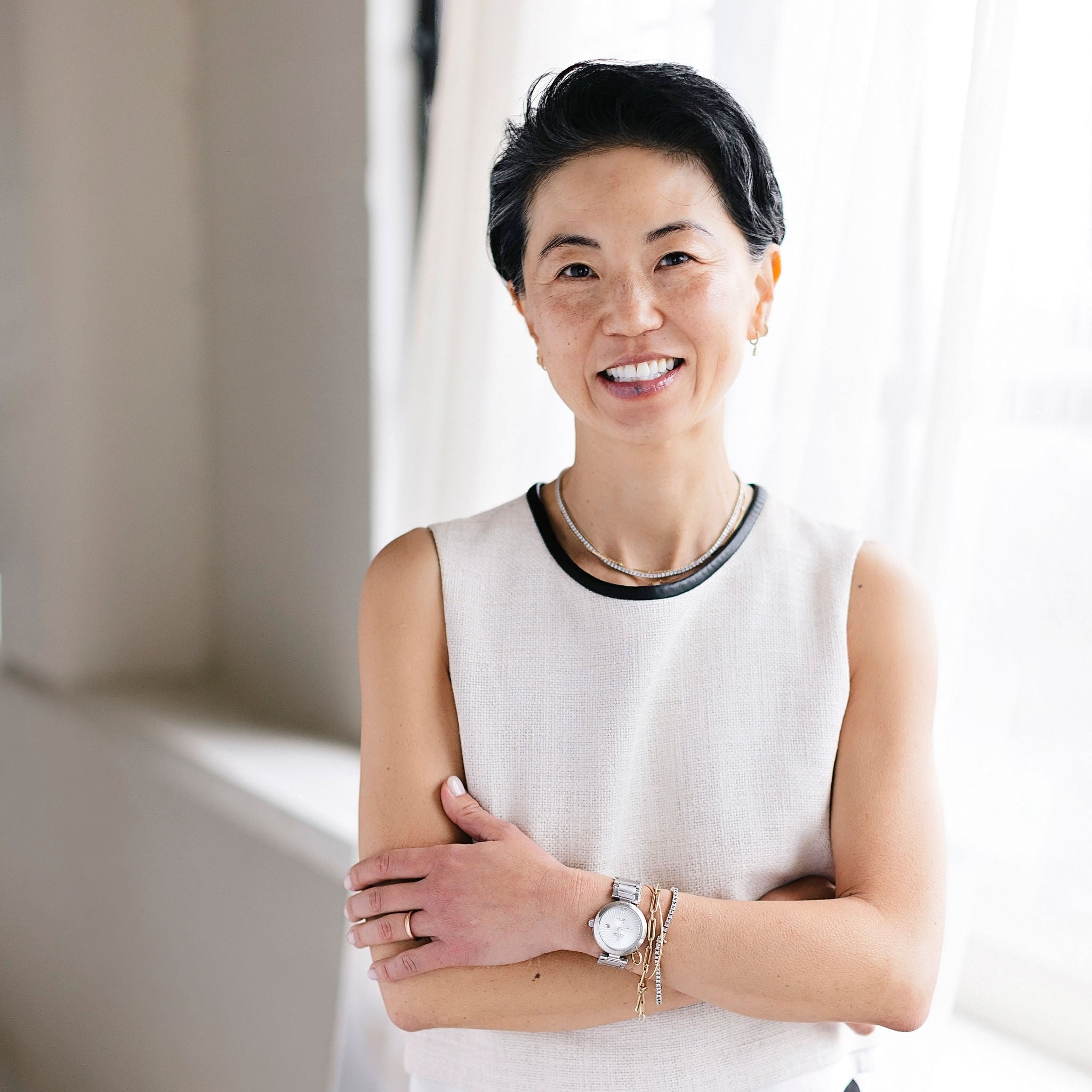 Woman standing indoors with a neutral background